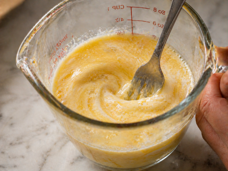 Wet ingredients — eggs, butter, milk and vanilla — whisked together in a glass measuring cup