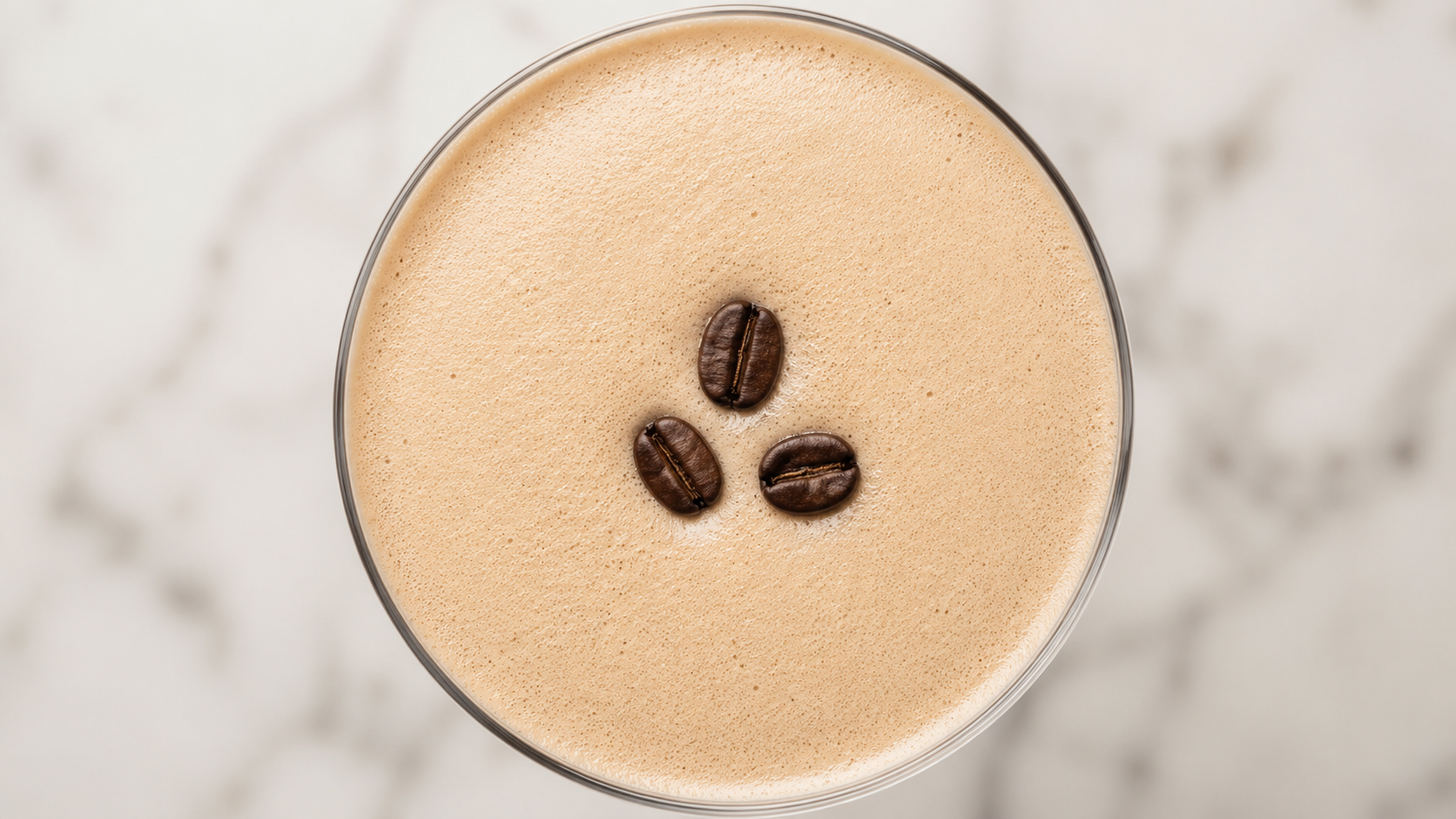 Three coffee beans placed on the foam of a finished espresso martini — classic garnish