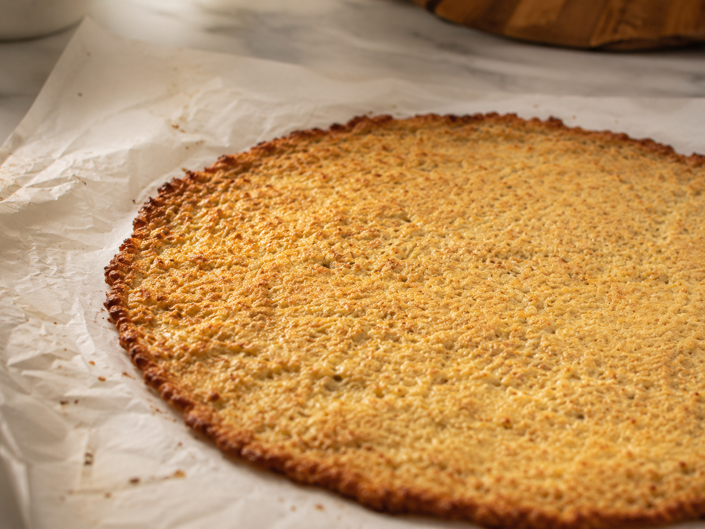Pre-baked cauliflower crust out of the oven — golden edges and set center