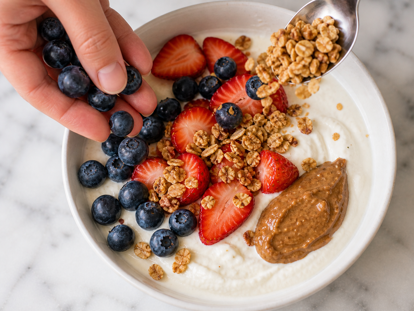 Fresh blueberries, granola and a spoonful of almond butter layered over the yogurt base