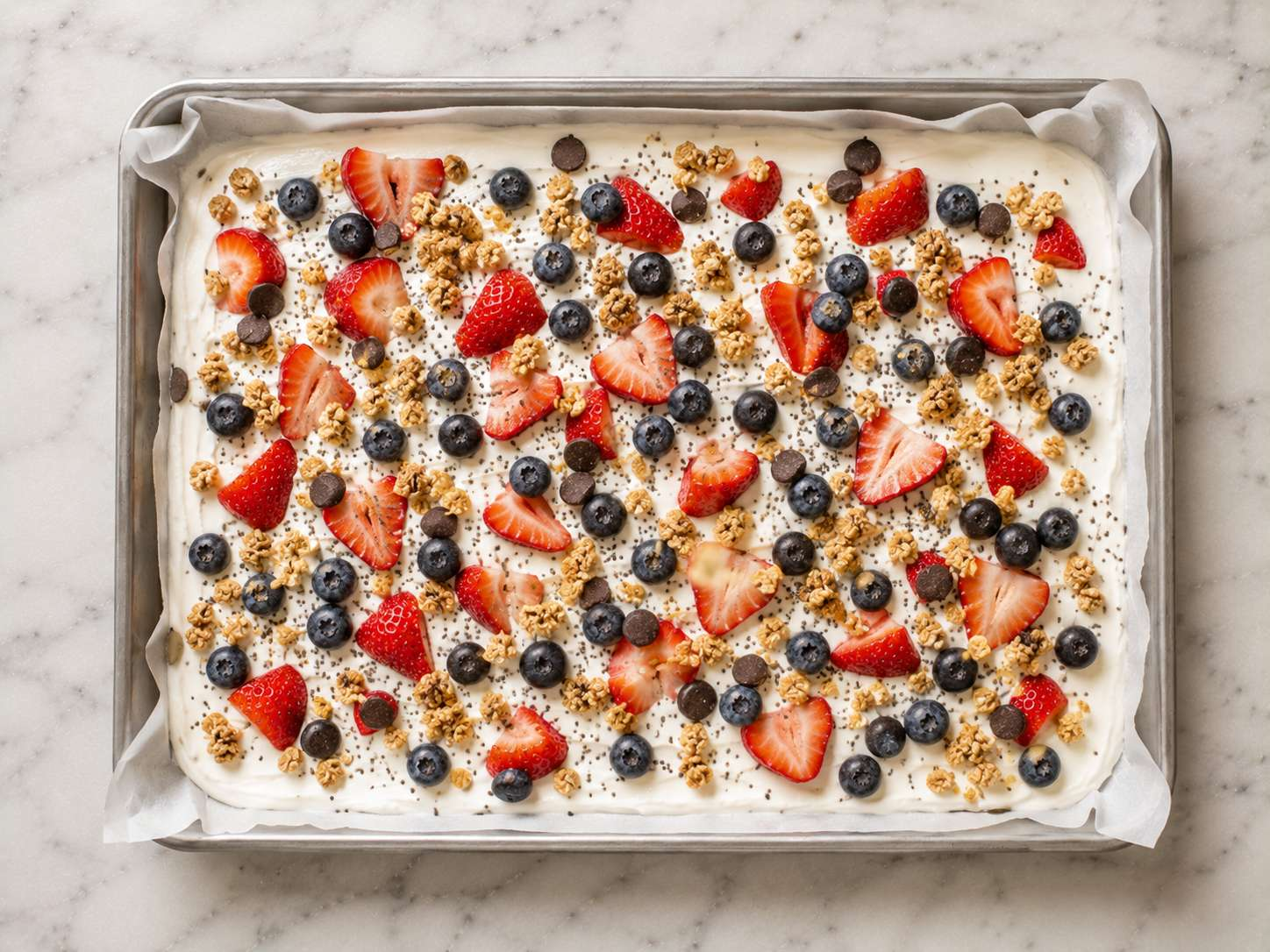 Strawberries, blueberries, granola and chocolate chips scattered over the yogurt layer