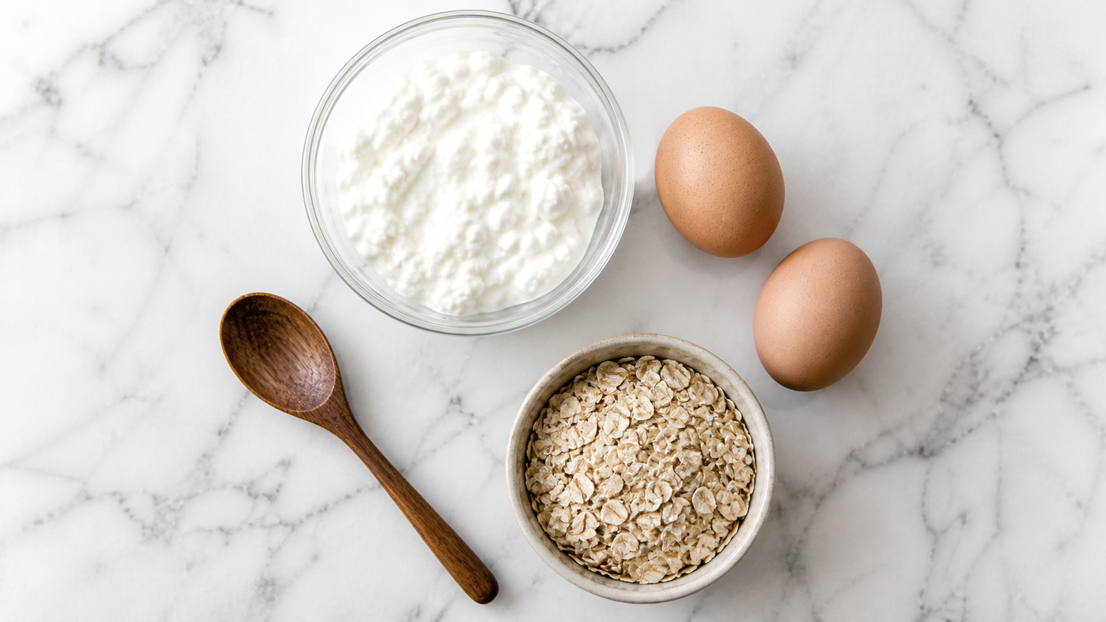 The three ingredients for cottage cheese pancakes laid out: cottage cheese, eggs, and rolled oats