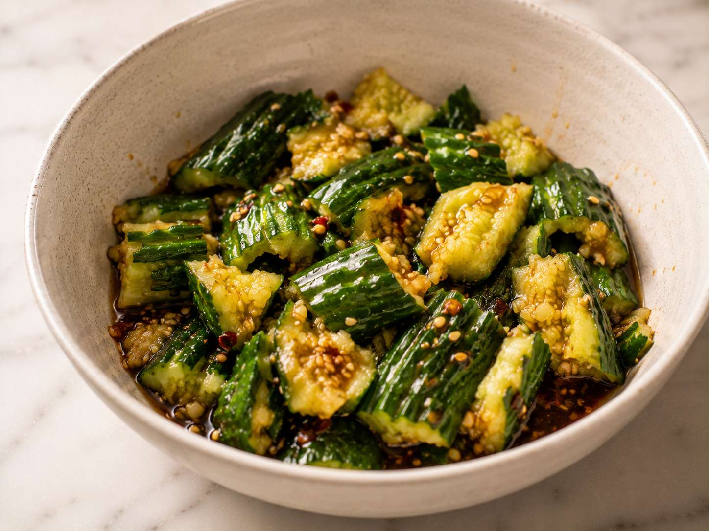 Finished asian cucumber salad topped with sesame seeds, sliced green onions and a drizzle of chili oil