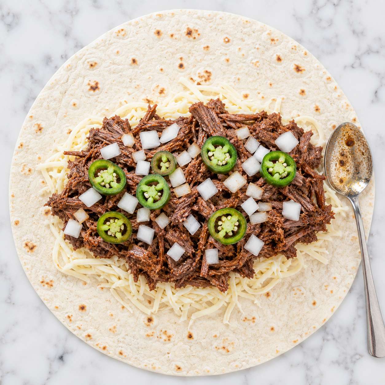 Warm tortilla layered with shredded cheese, seasoned beef and diced onion — ready to roll