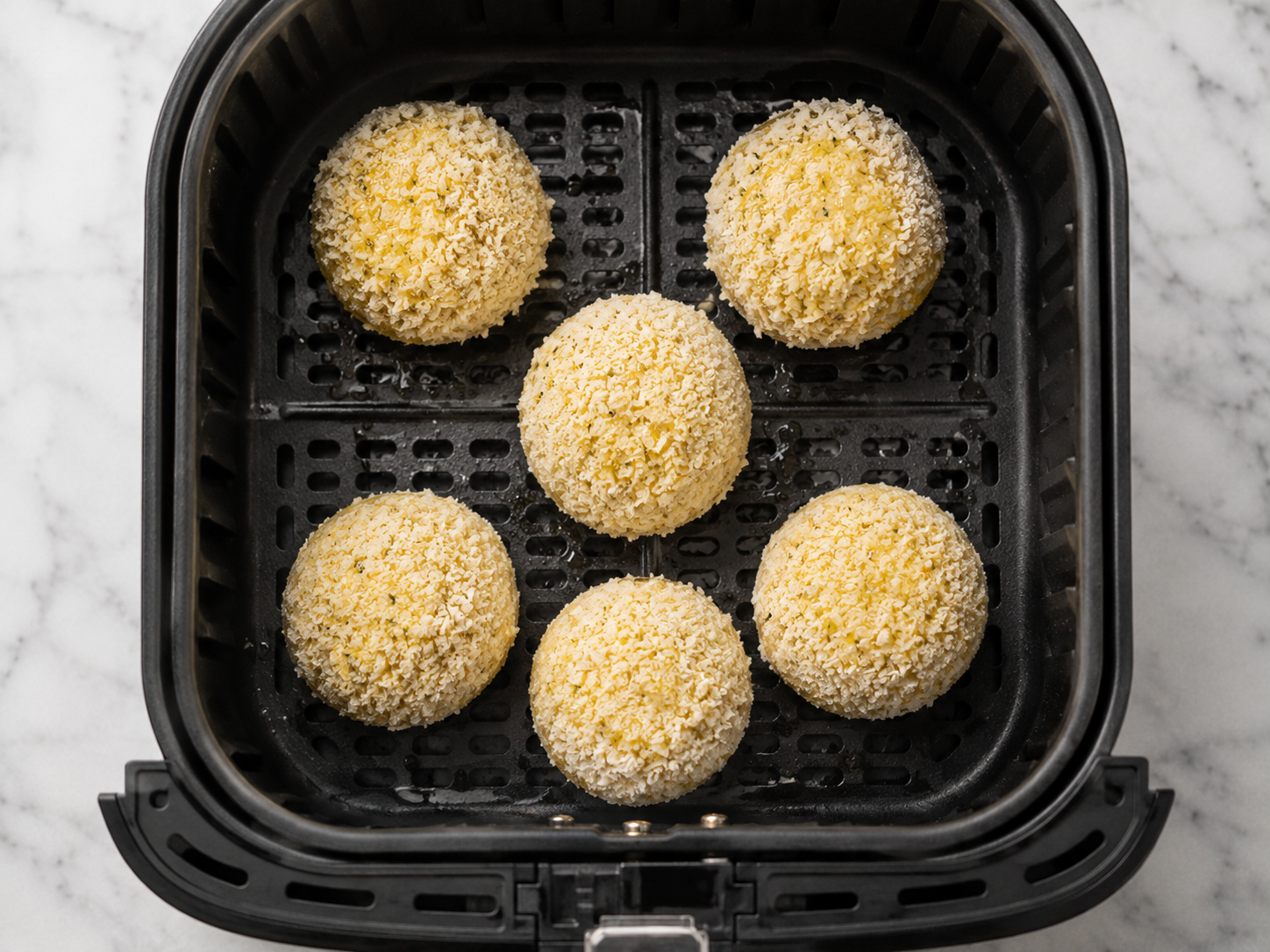 Breaded potato croquettes arranged in a single layer in the air fryer basket — sprayed with olive oil and ready to cook