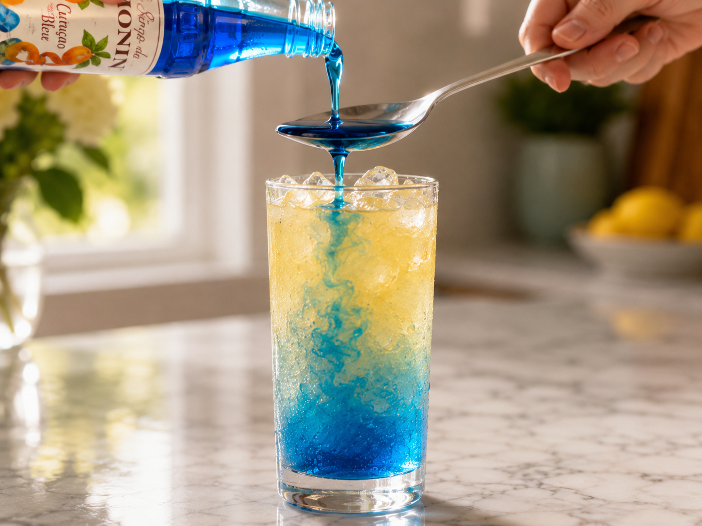 Blue curacao syrup poured slowly over the back of a spoon — sinking and swirling into the glass beautifully