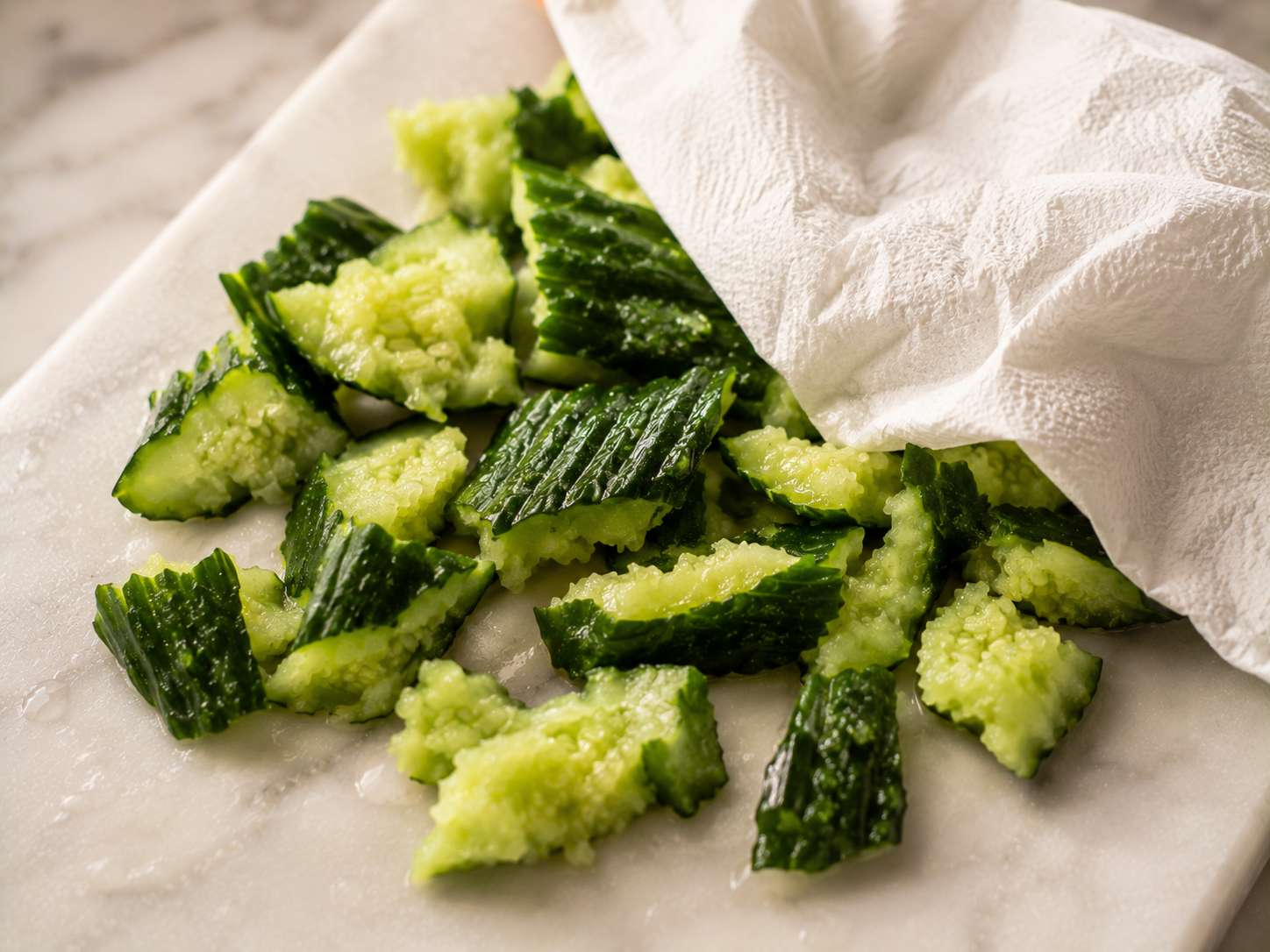 Cucumber pieces tossed with the sesame-garlic dressing in a large mixing bowl