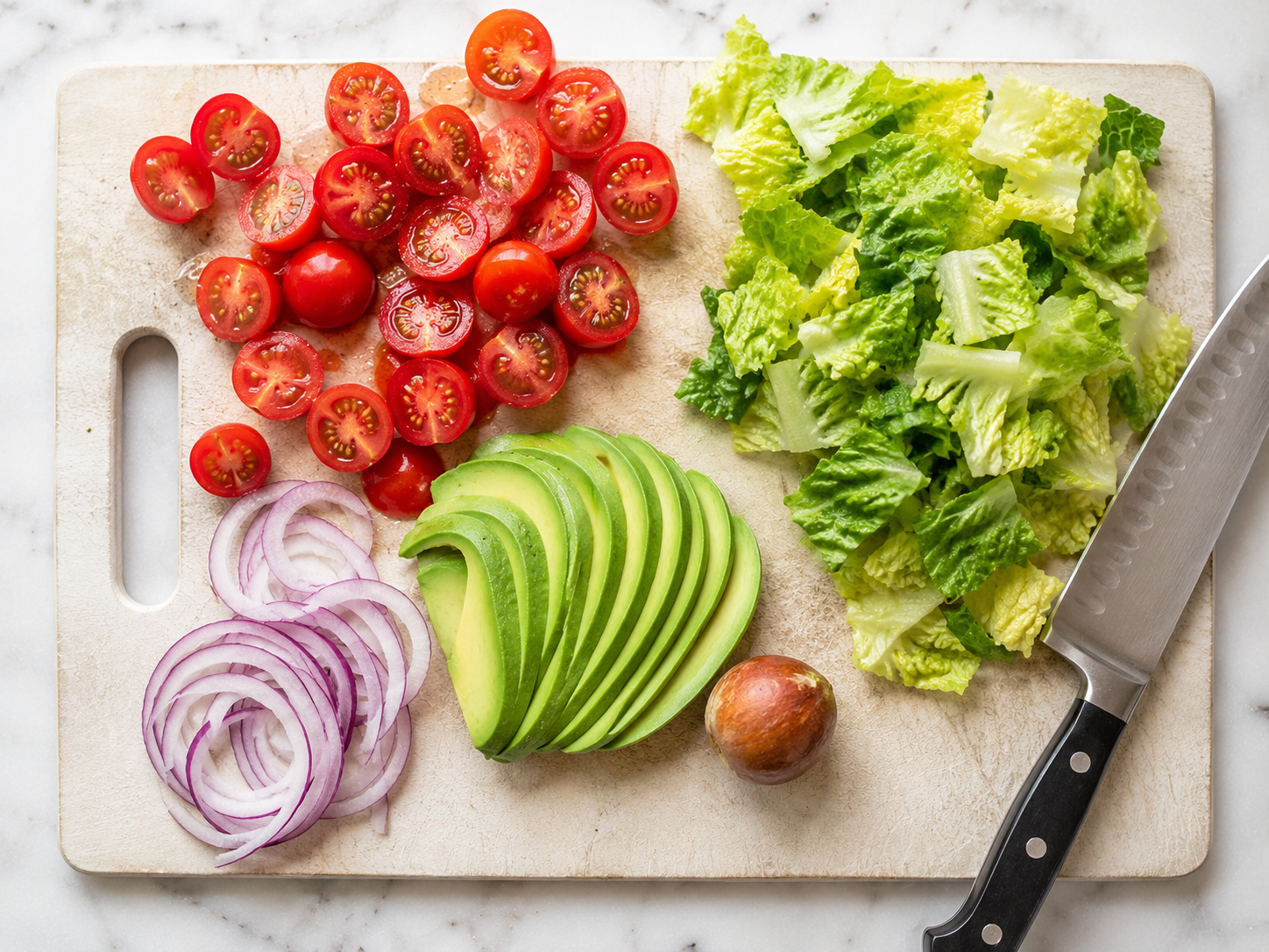 All salad vegetables prepped and ready — chopped romaine, halved tomatoes, sliced avocado and red onion