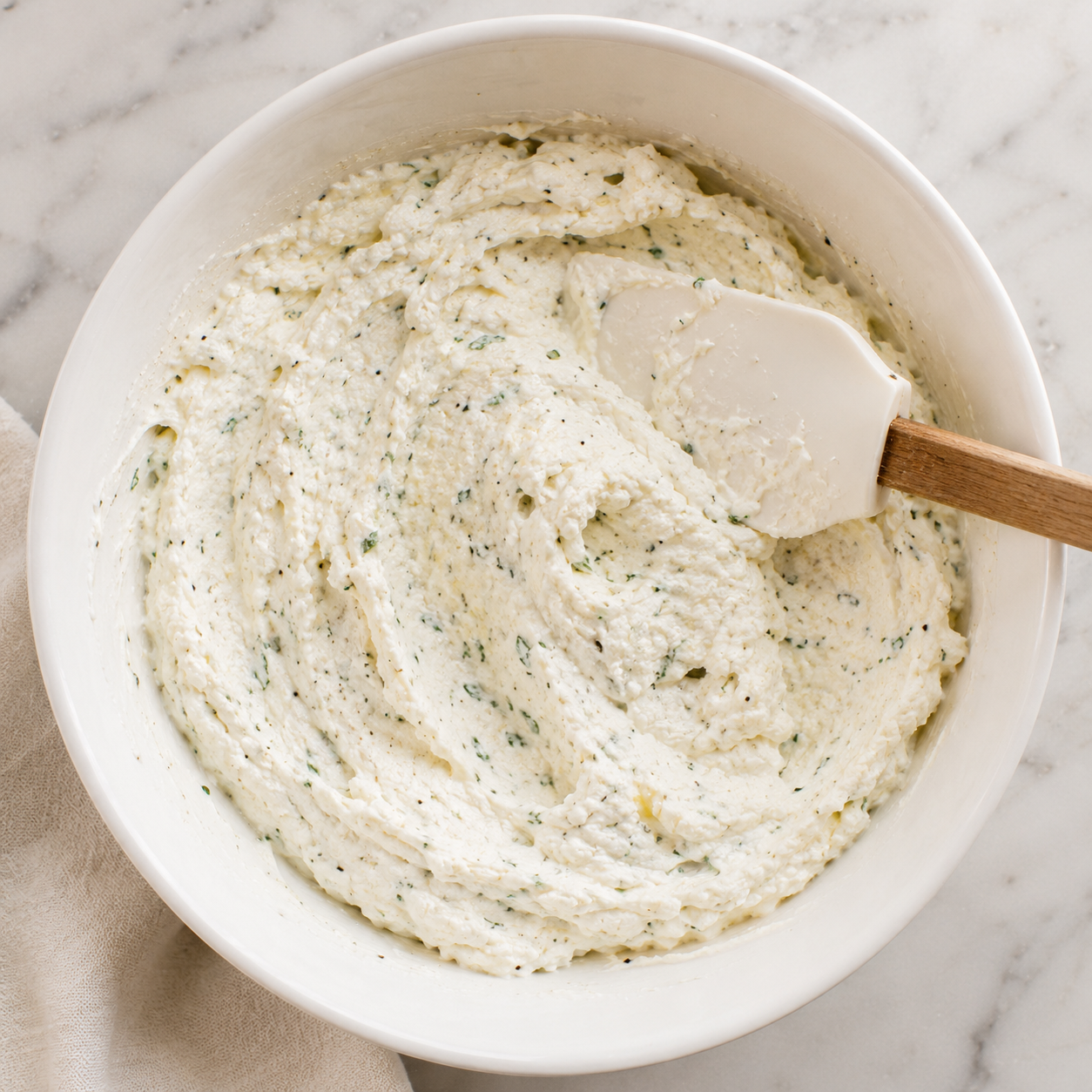 Ricotta filling mixed with egg and Italian seasoning in a bowl — smooth and ready to layer