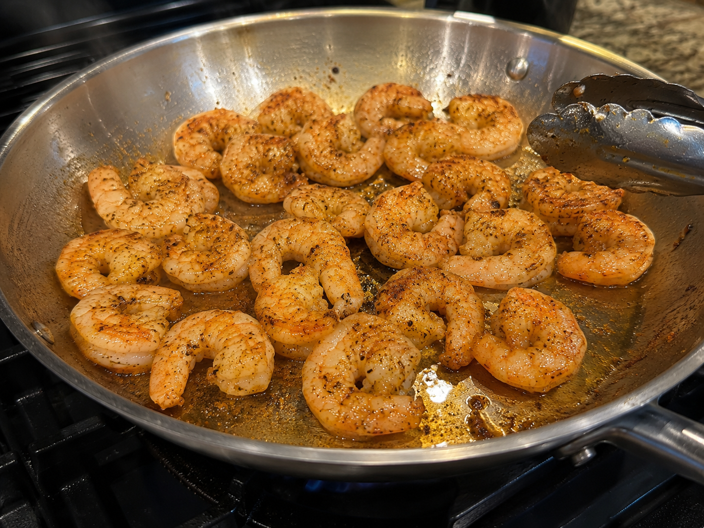 Shrimp searing in a hot skillet — turning pink and golden on the edges