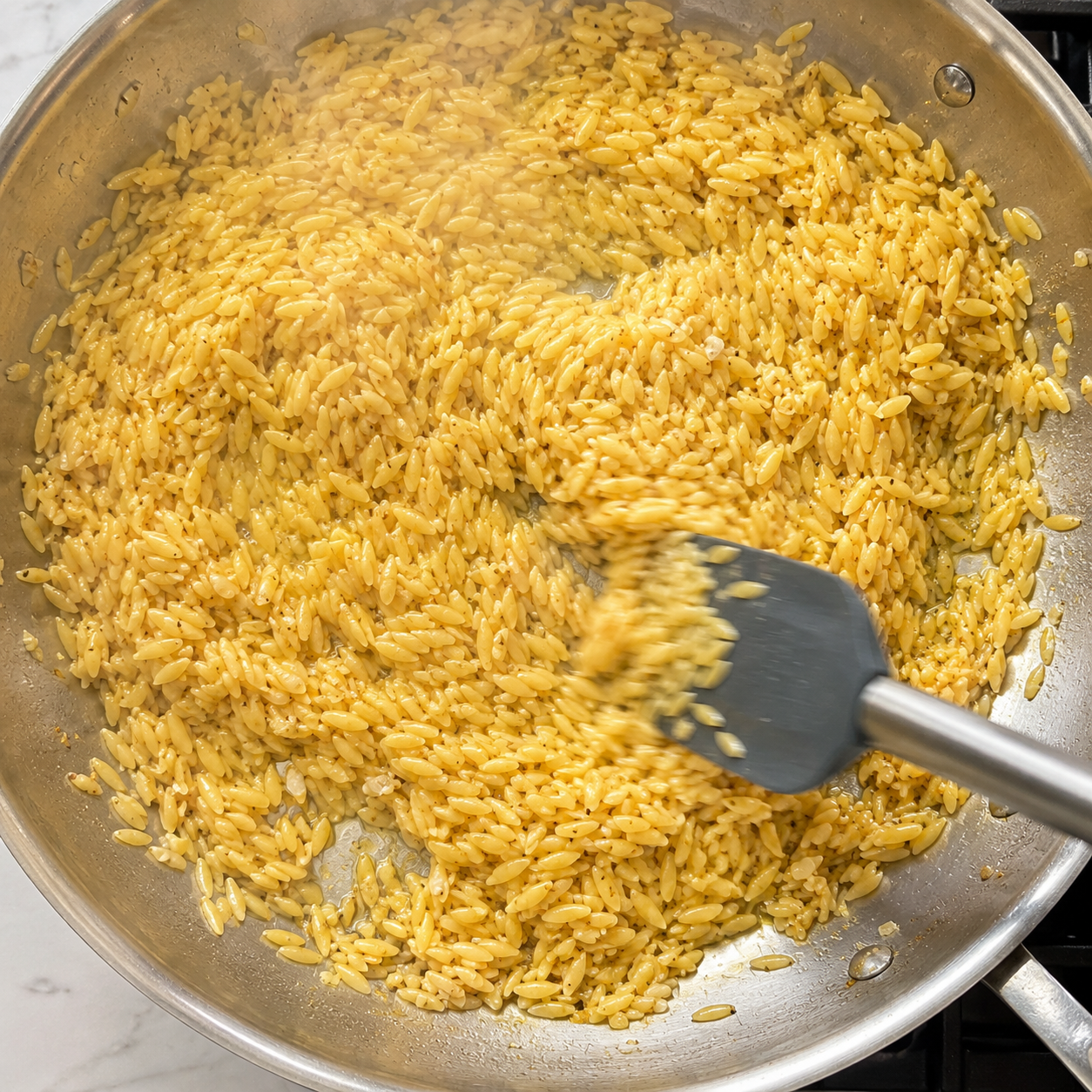 Dry orzo toasting in the garlic butter pan — turning lightly golden