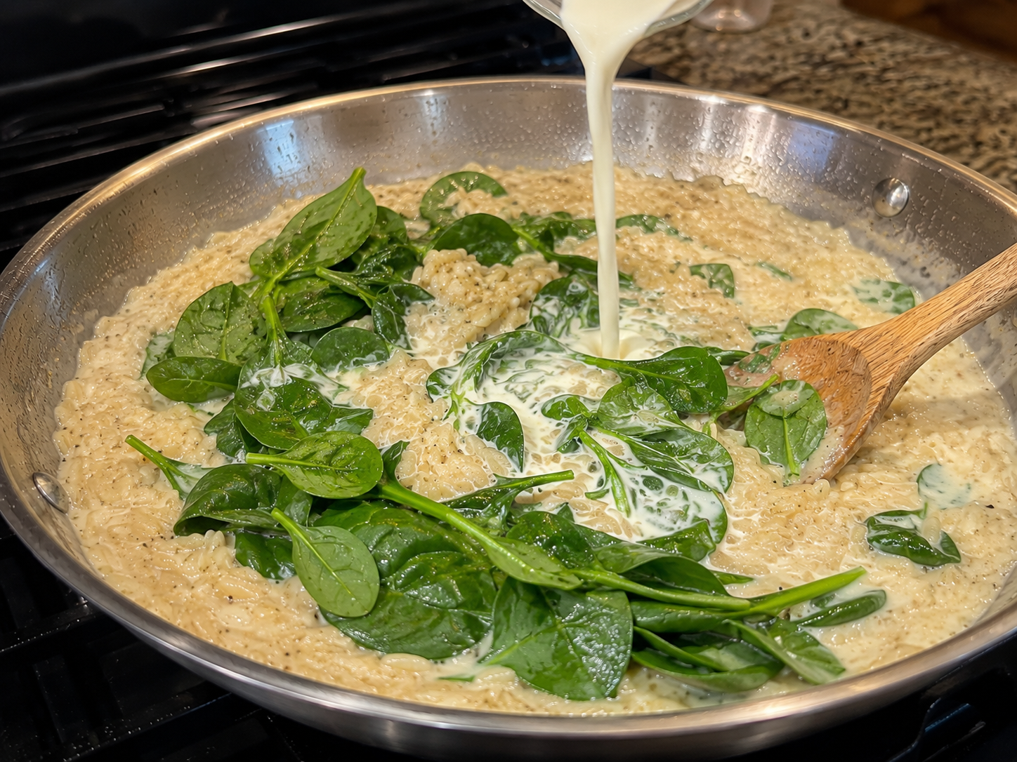 Heavy cream and fresh baby spinach added to the simmered orzo — spinach wilting into the sauce
