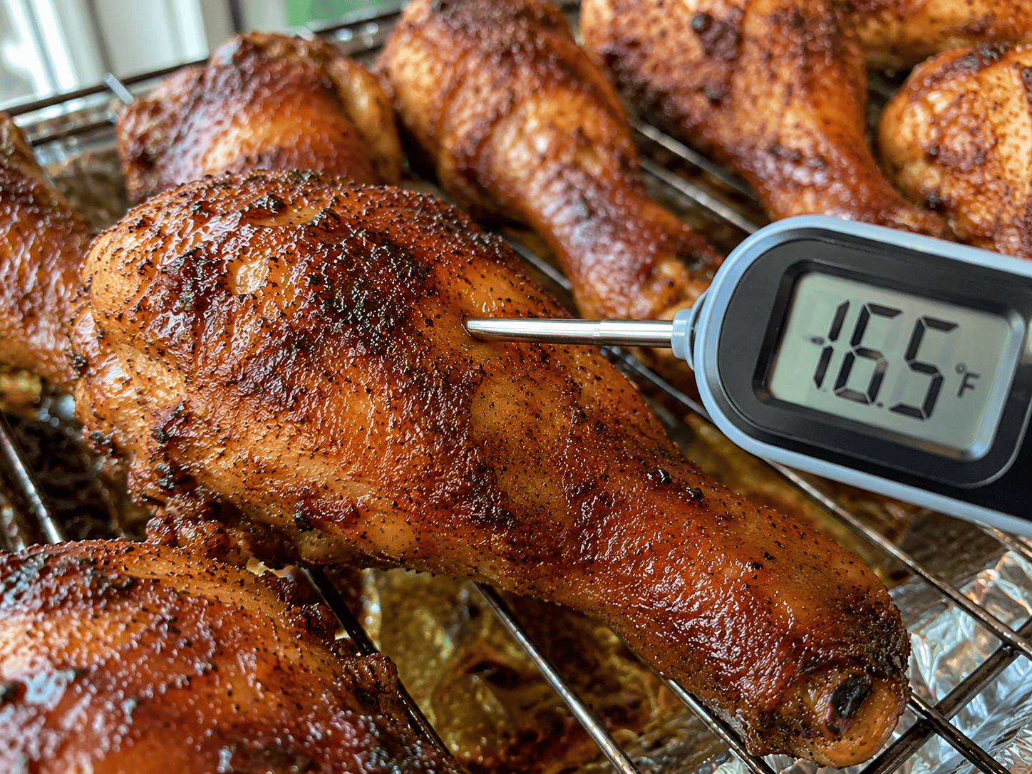 Meat thermometer inserted into the thickest part of a baked drumstick — reading 165°F