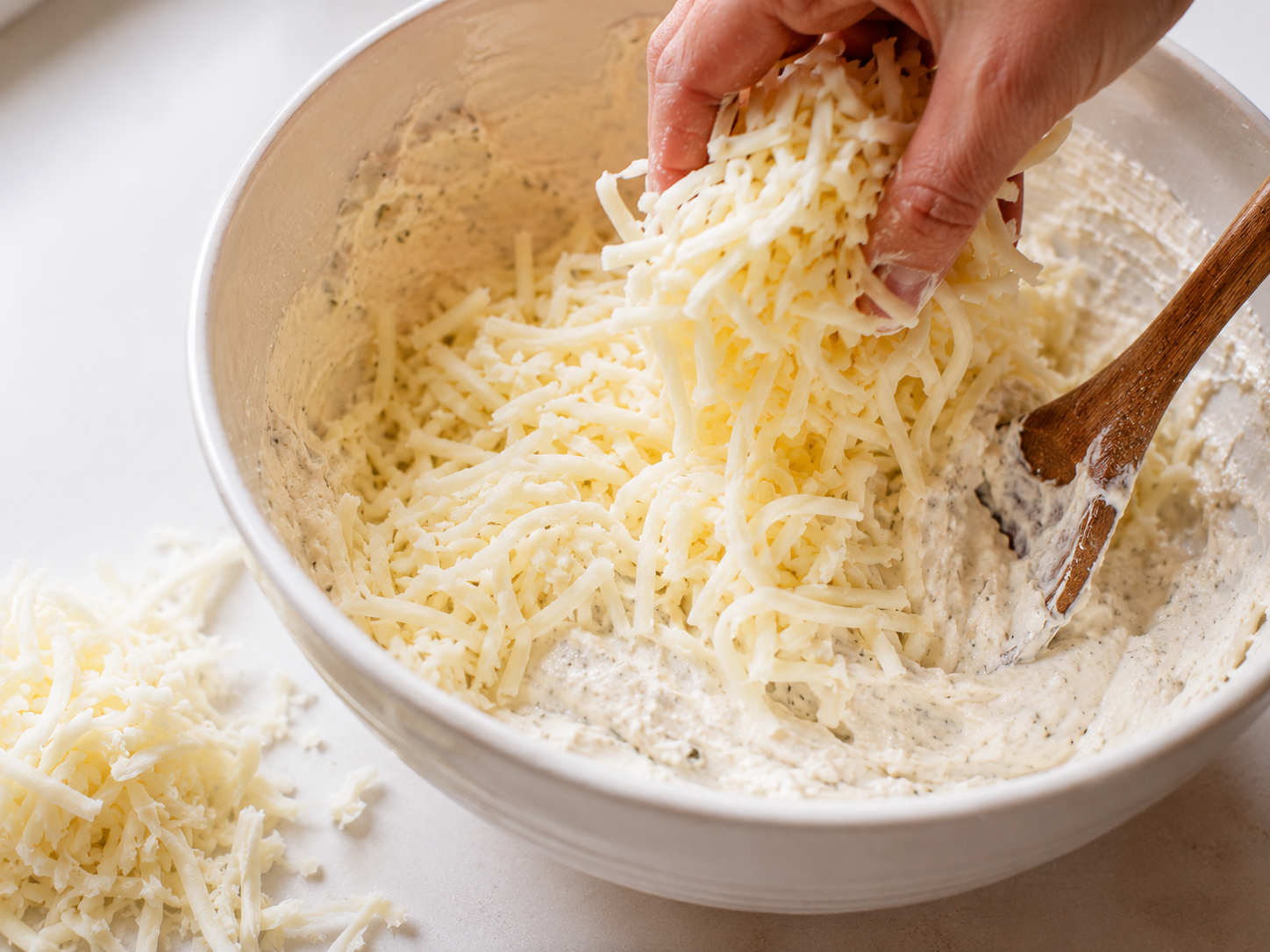Folding shredded mozzarella and parmesan into the cream cheese dip base
