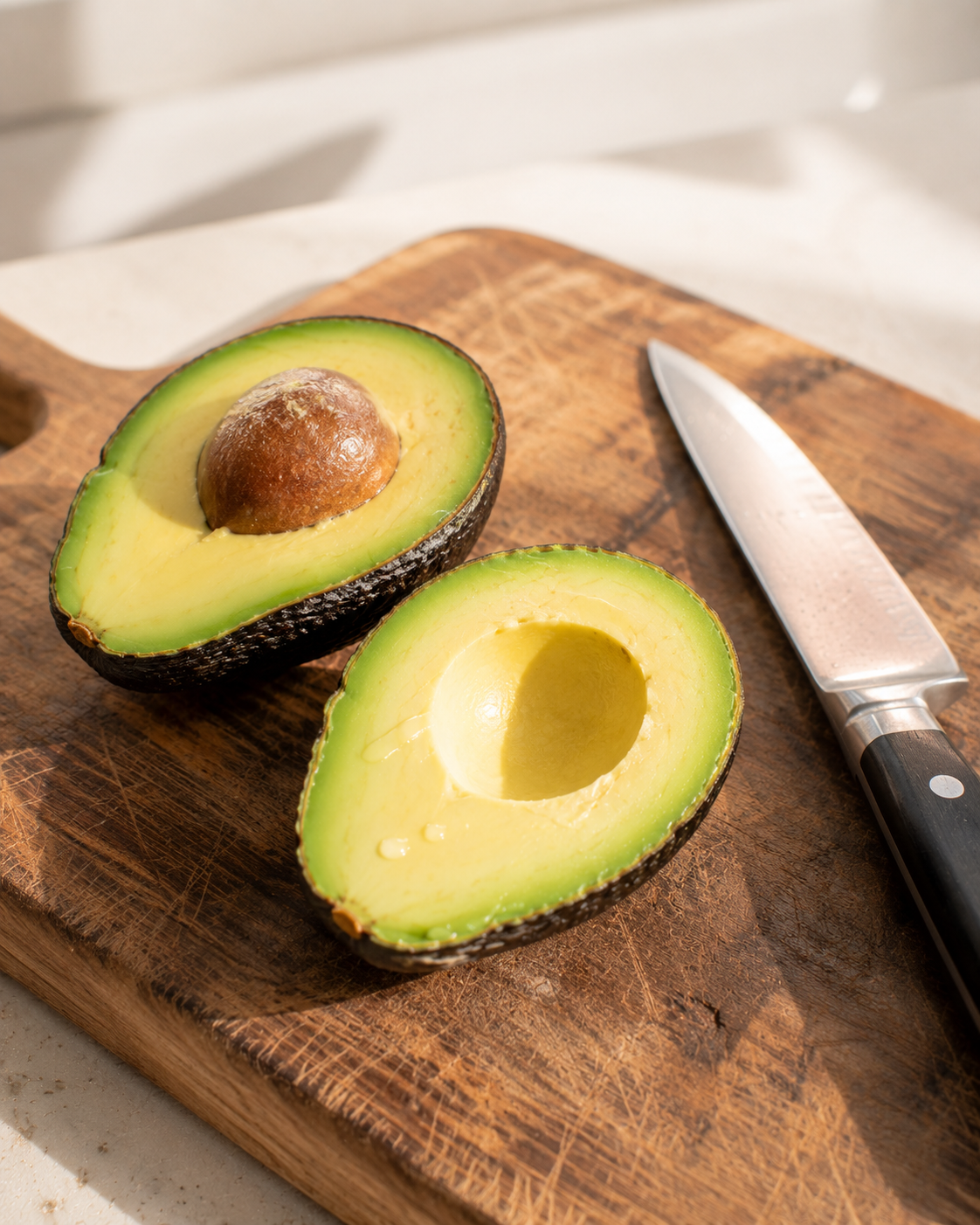 Halving ripe avocados on a wooden board and removing the pit