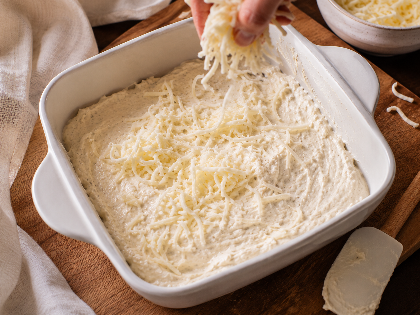 Cheesy dip mixture spread into a baking dish and topped with reserved mozzarella — ready to bake