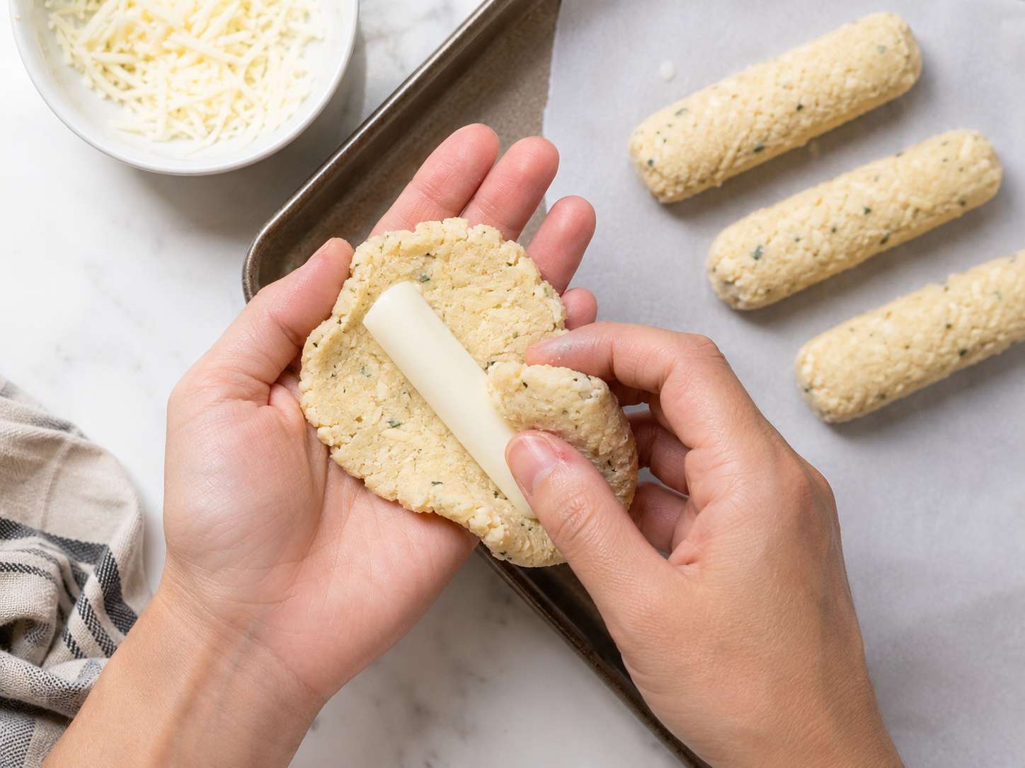 Wrapping a half string cheese stick in cauliflower dough — shaping and sealing into a stick
