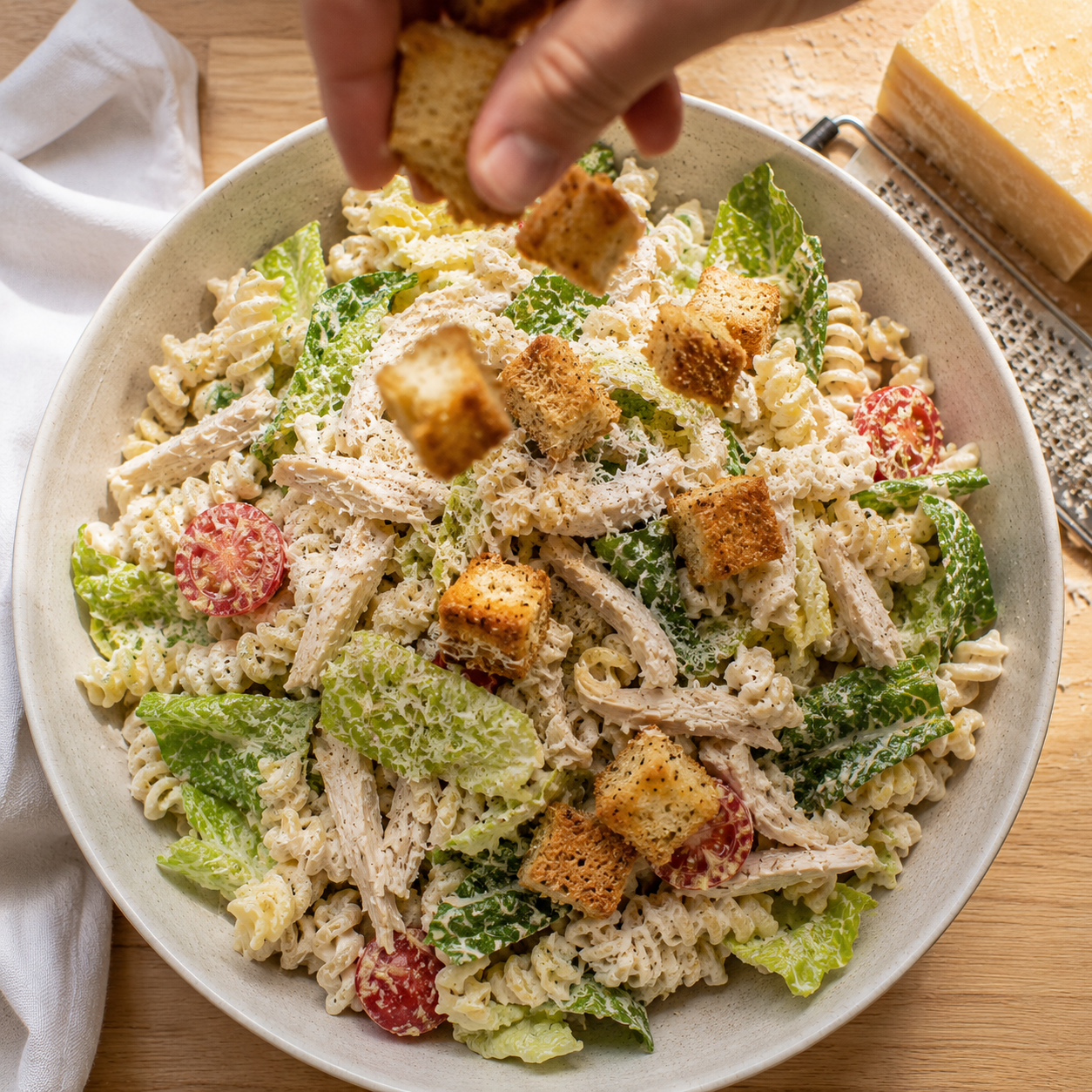 Finished chicken Caesar pasta salad topped with croutons and freshly grated parmesan — ready to serve
