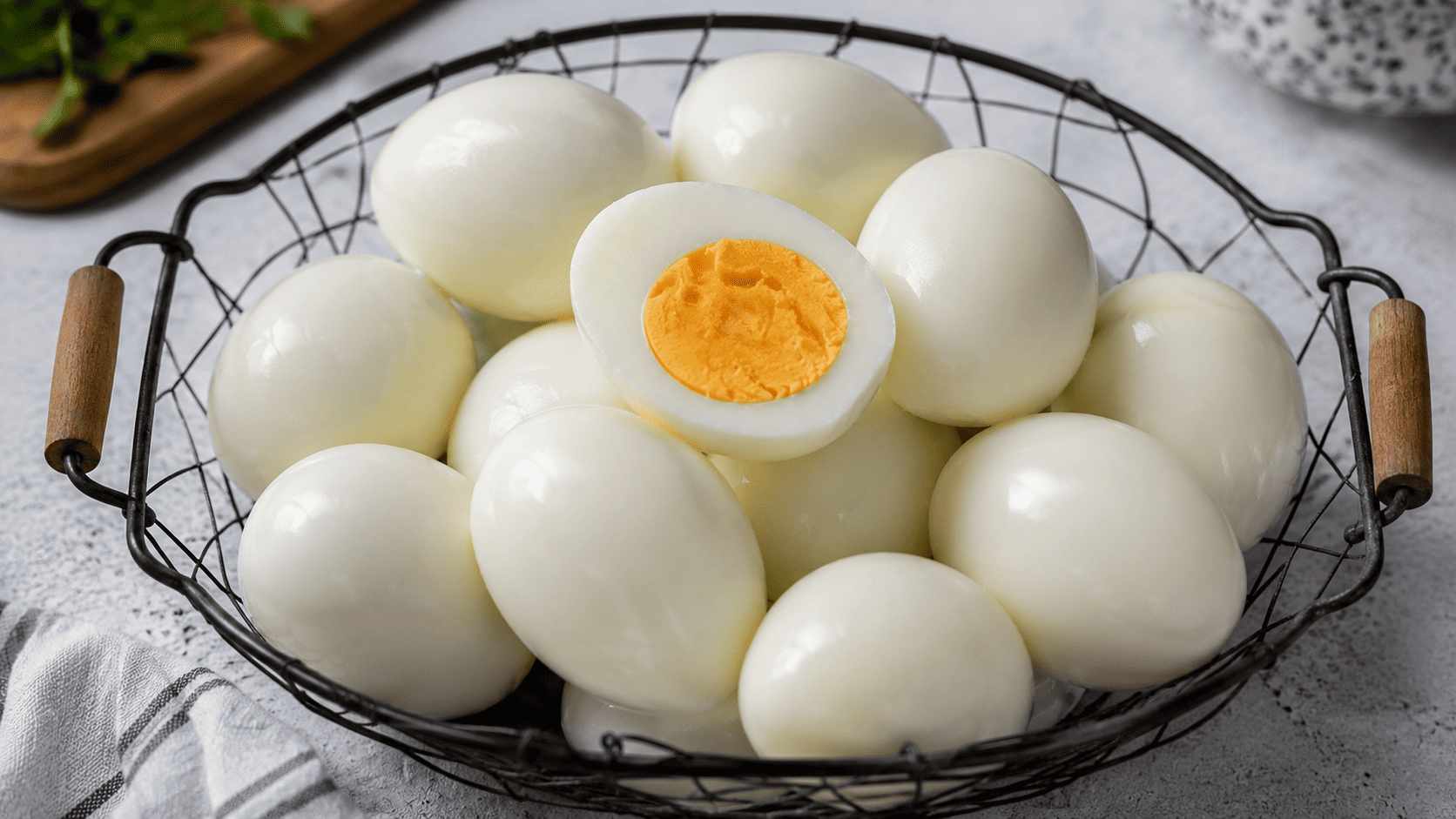 A dozen peeled hard boiled eggs in a wire basket