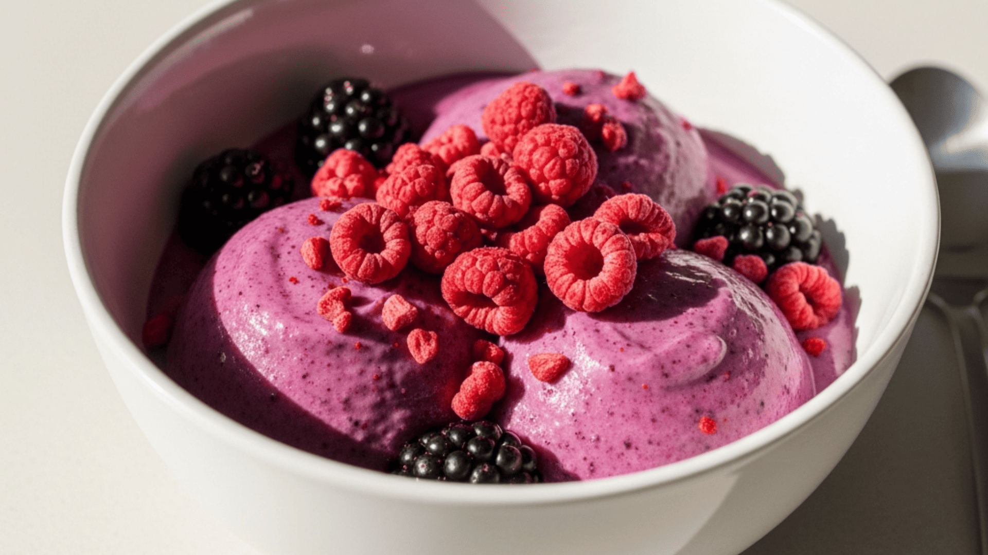 Bright fruit-punch-purple triple-berry bowl with freeze-dried raspberries on top