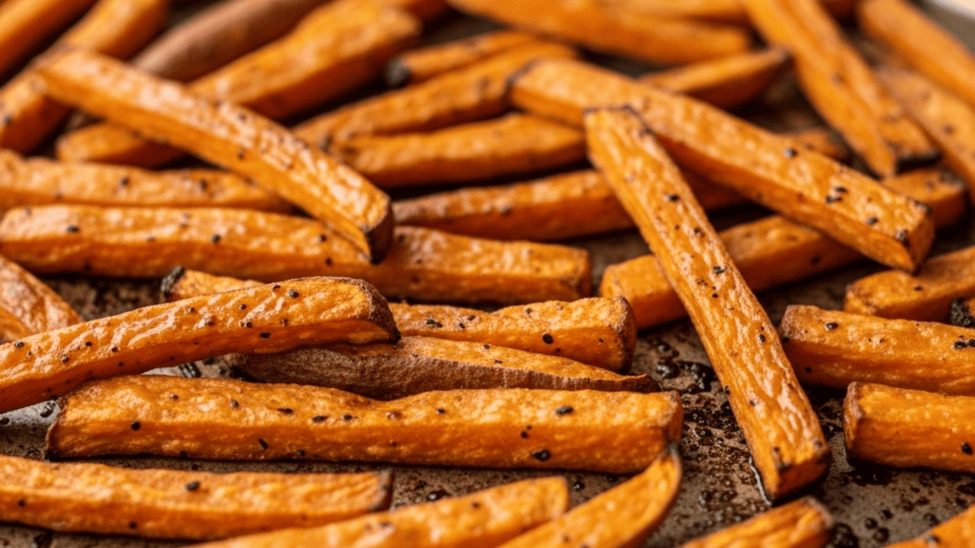 Crispy baked sweet potato fries on a sheet pan, golden and lightly charred