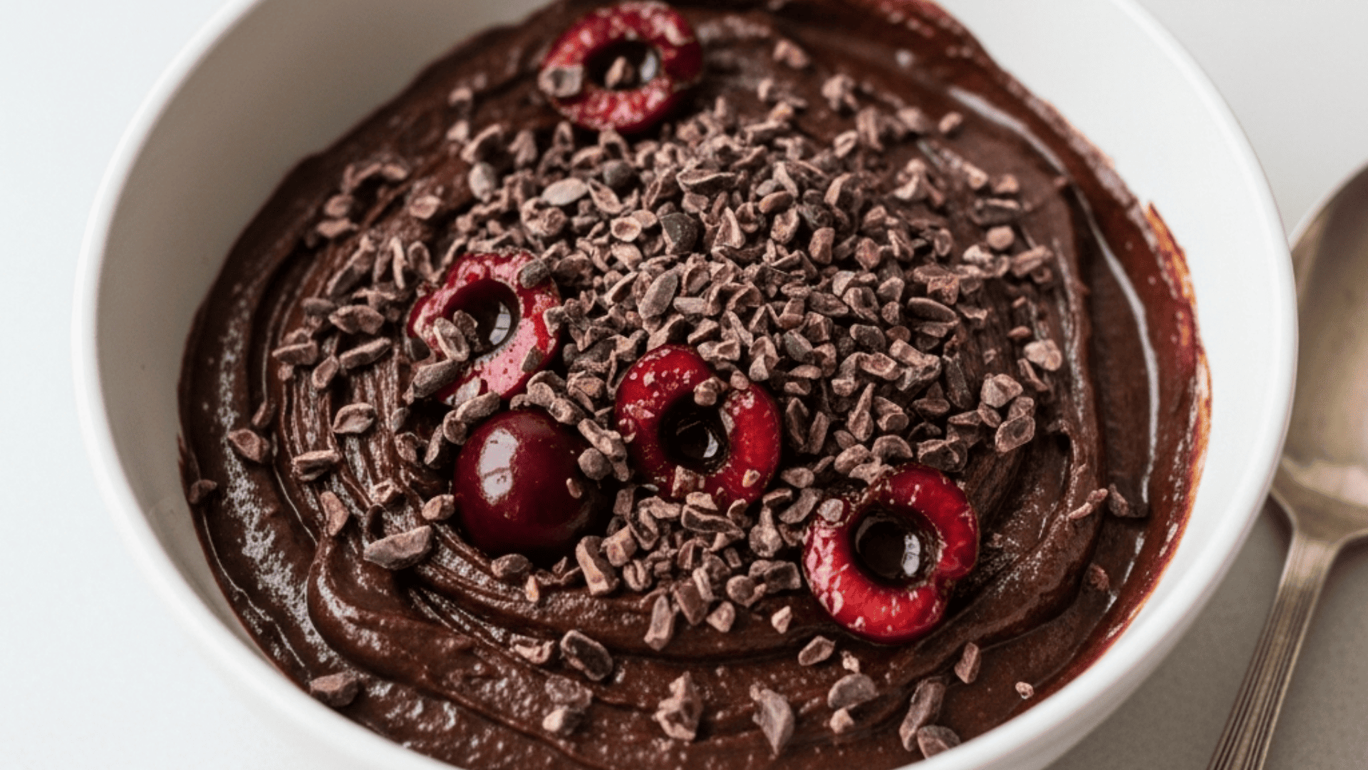 Dark chocolate-cherry brownie batter bowl with cacao nibs, cherries and dark-chocolate shavings