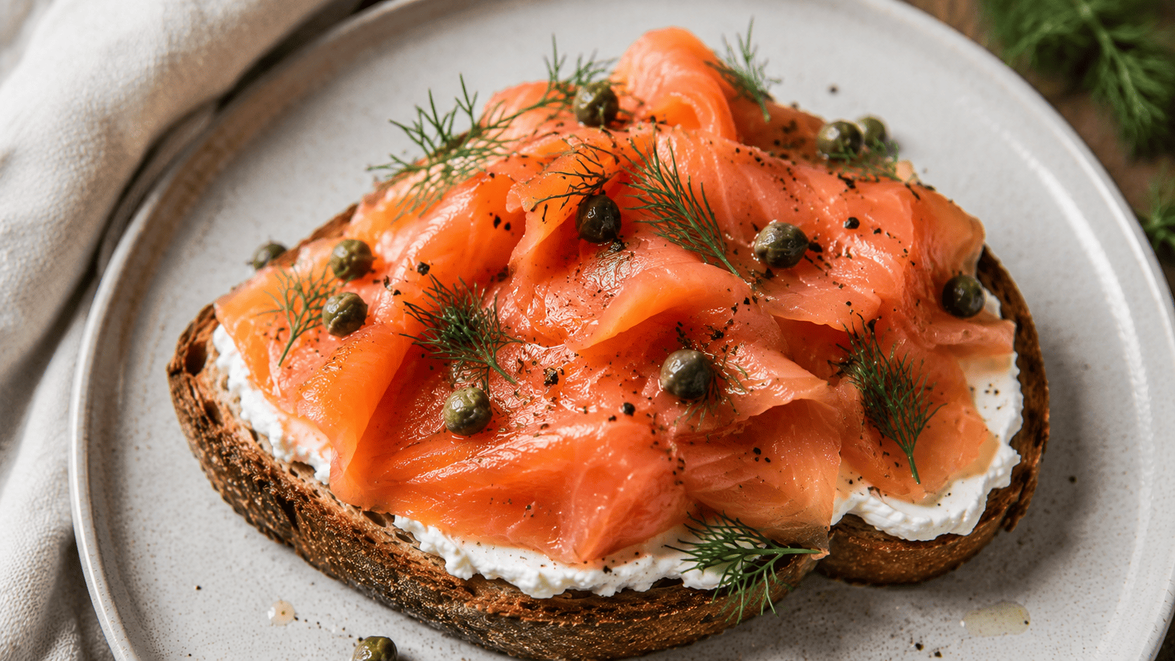 Draped smoked salmon over cream cheese toast with capers and fresh dill
