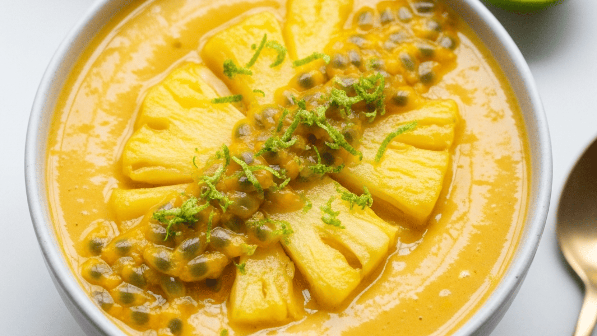 Golden pineapple smoothie bowl with fresh passionfruit pulp and lime zest