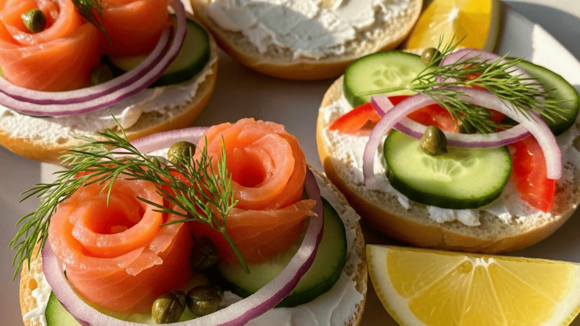 Smoked salmon and bagel bar board — halved mini bagels, cream cheese, smoked salmon folded into rosettes, capers, red onion, cucumber, dill and lemon wedges