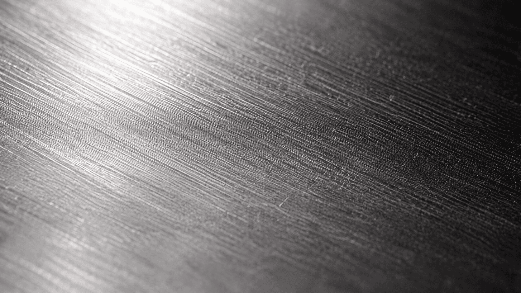 Macro close-up of polished stainless steel surface showing microscopic texture under raking light