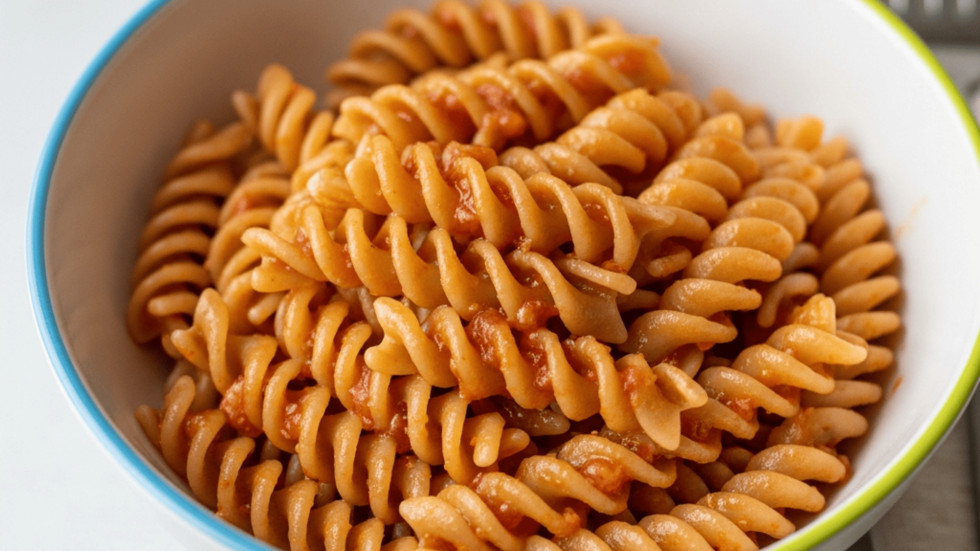 Buttered whole-wheat pasta in a kid-sized bowl, simple and steaming