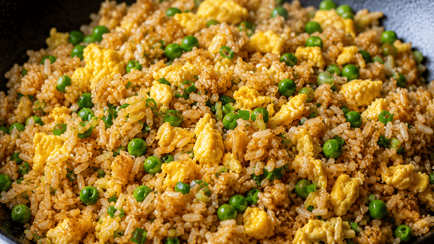 Wok-tossed fried rice with visible egg ribbons and green peas, glossy sheen from hot oil, close-up texture shot