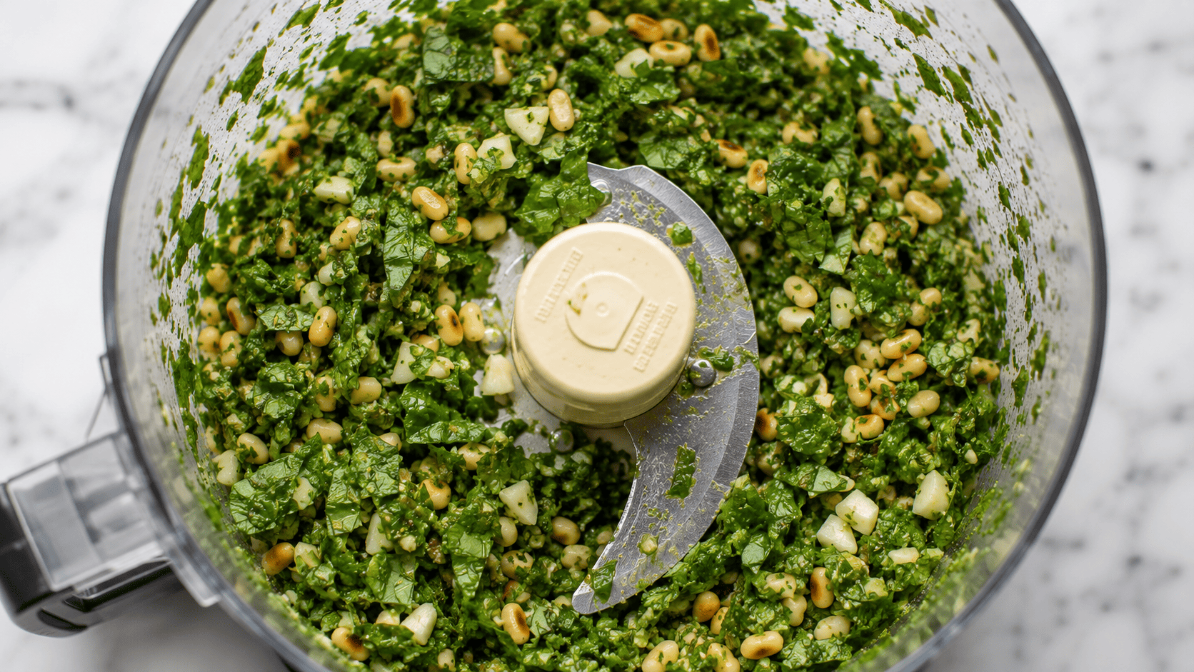 Basil, pine nuts, and garlic finely chopped in a food processor bowl