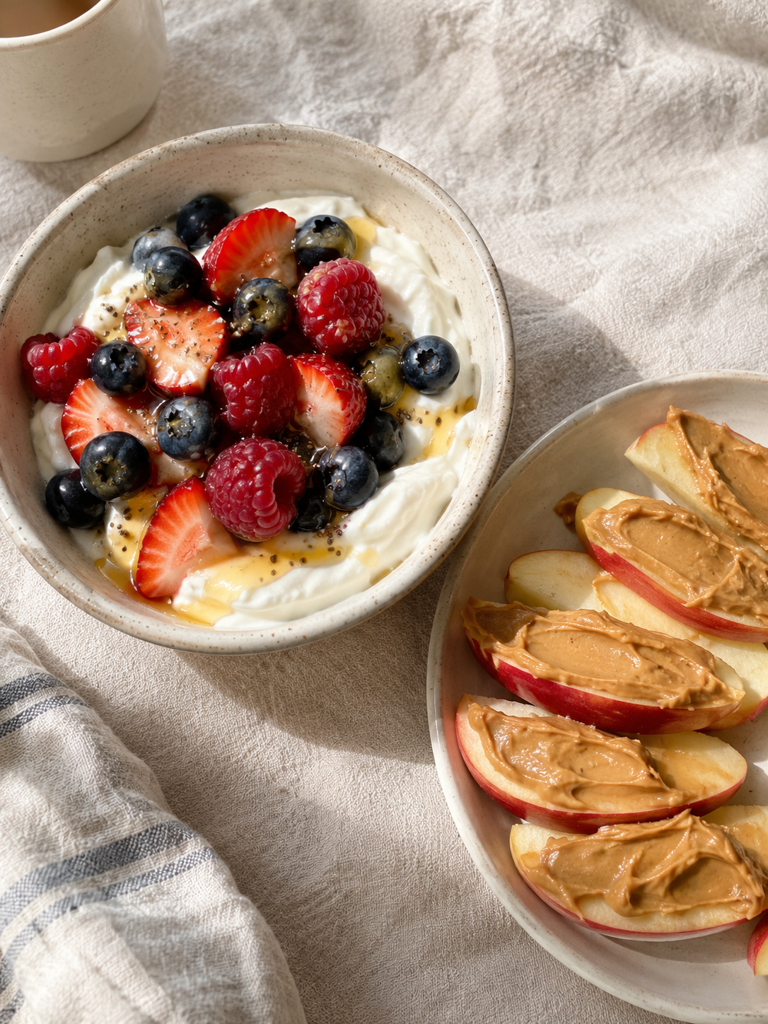 Greek yogurt with berries and honey next to apple slices with peanut butter, two quick healthy snacks