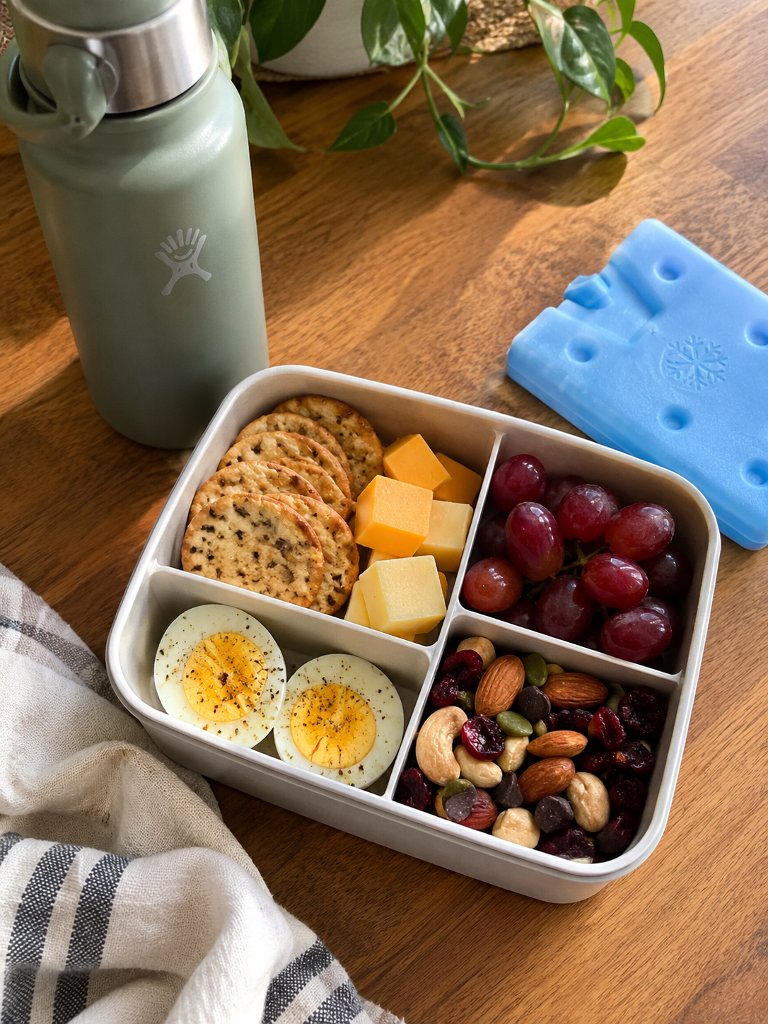 Bento-style healthy snacks on the go with crackers, cheese, fruit and veggies packed for a picnic