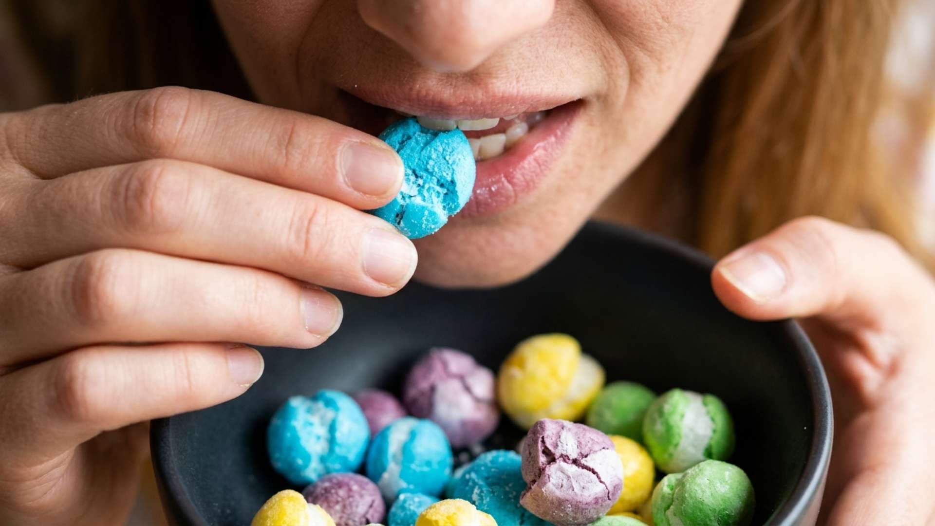 Chewy candy inflating inside a glass freeze-dryer door and a hand snapping a freeze-dried candy in half