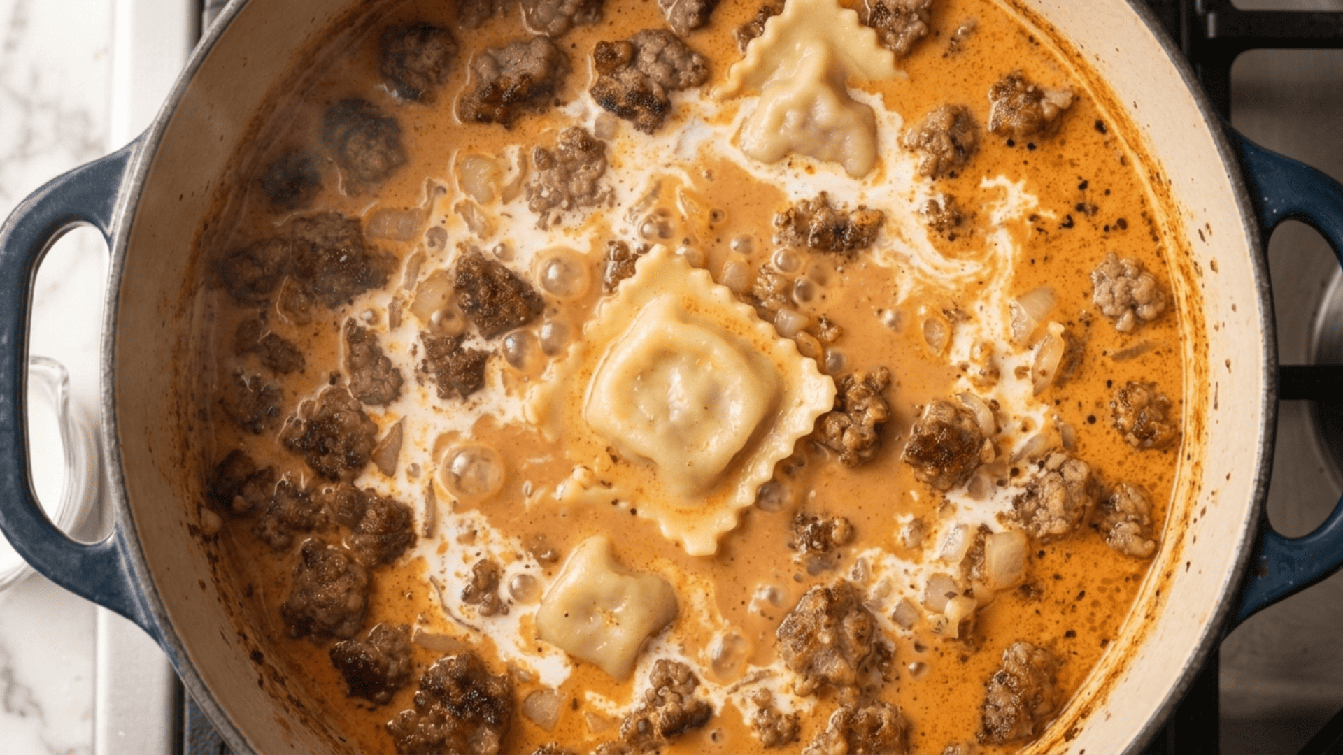 Cheese ravioli being added to a creamy tomato soup base