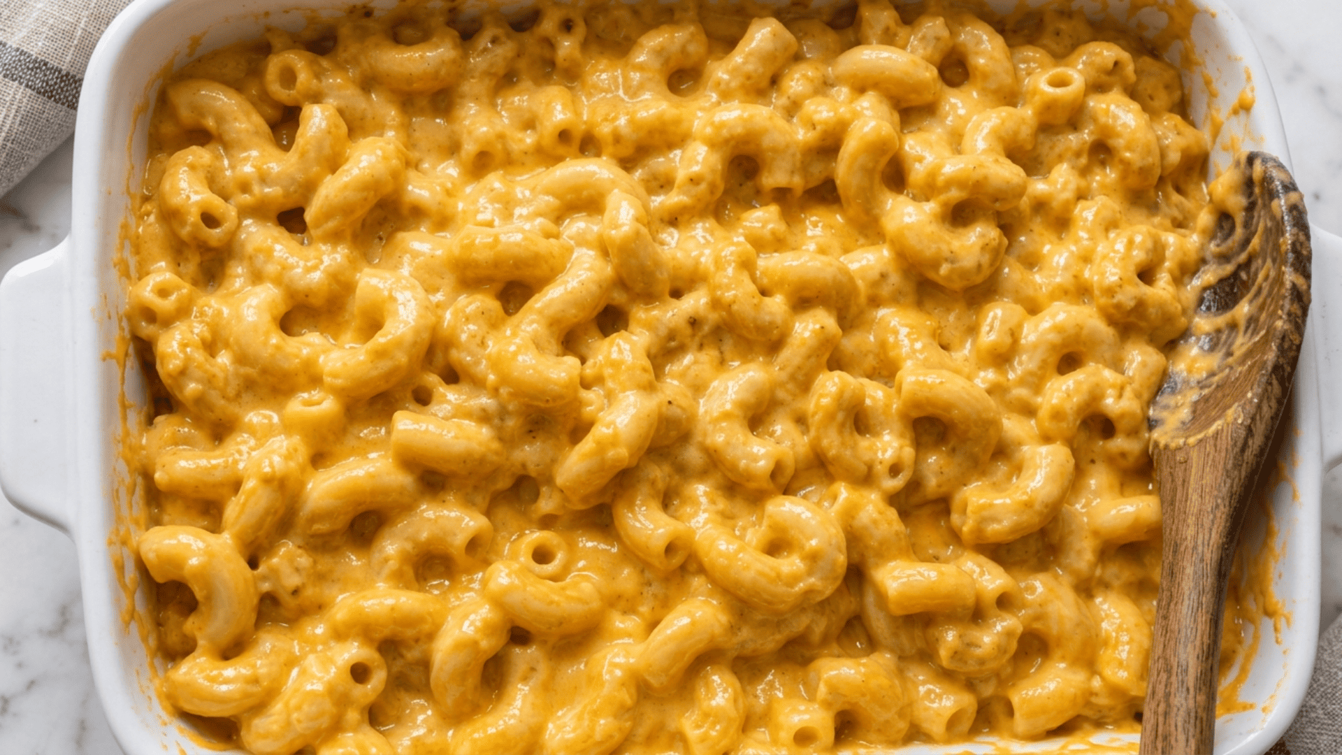 Creamy butternut squash mac and cheese spread into a baking dish before the topping