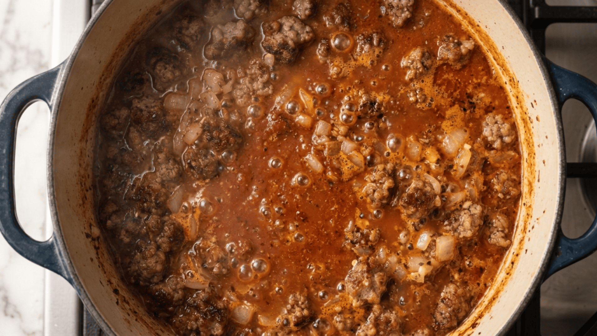 Tomato and sausage broth simmering in a Dutch oven