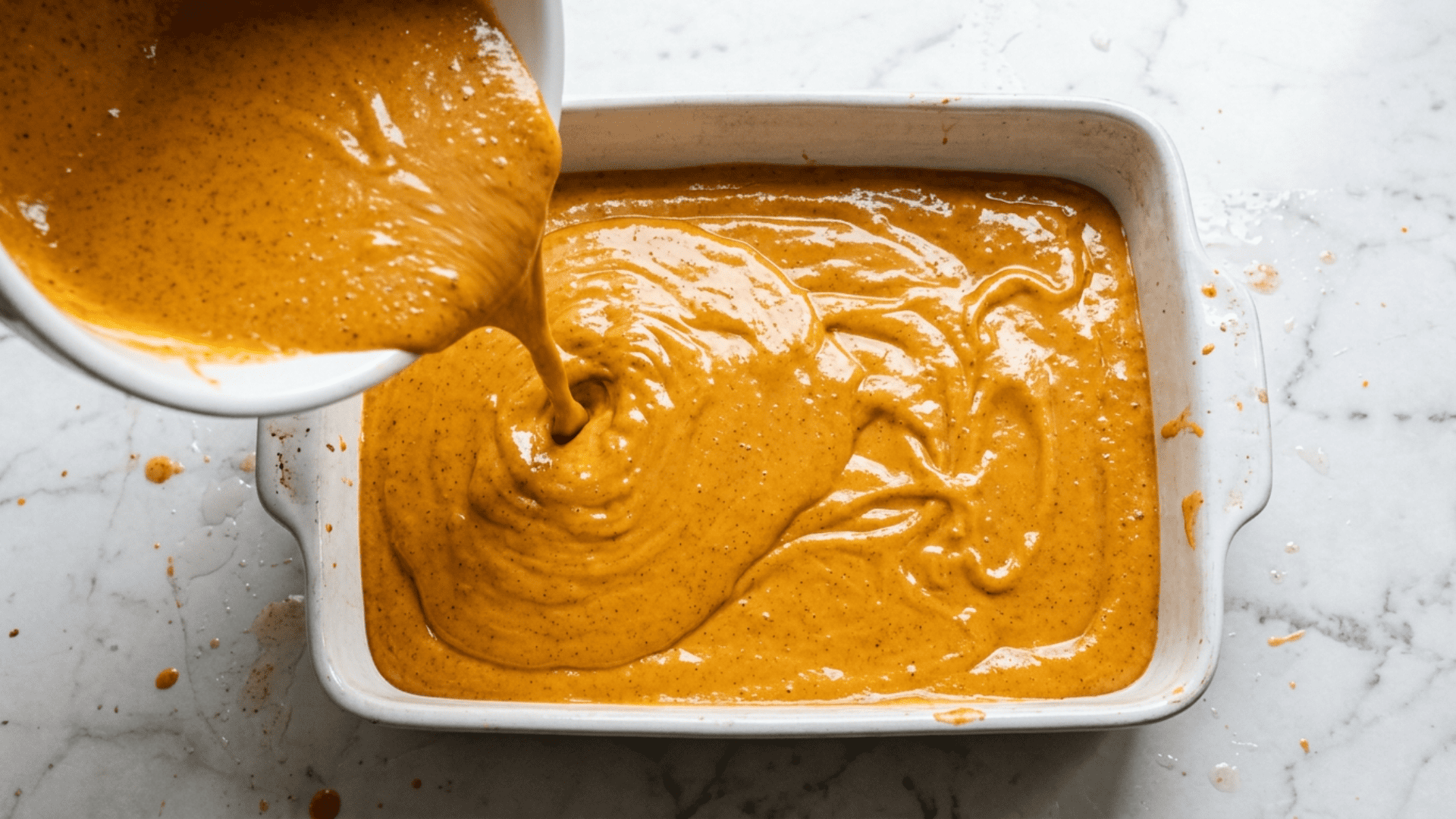 Smooth orange pumpkin filling poured into a greased baking dish